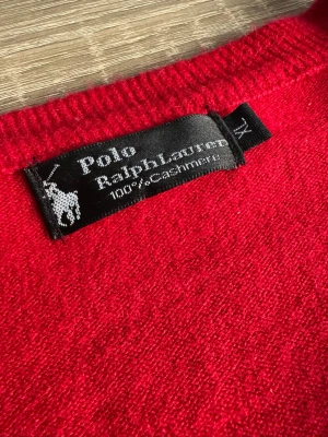 Röd cashmere-tröja Polo Ralph Lauren - Klassisk röd stickad tröja från Polo Ralph Lauren. Tröjan har rund halsringning och den ikoniska broderade loggan på bröstet. 