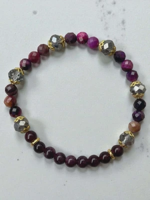 Färgglatt ametist kristaller och med gulddetaljer - Snyggt armband med facetterade pärlor i lila, vinrött och silver, dekorerat med små guldfärgade detaljer. Perfekt accessoar för att lyfta din outfit med lite extra färg och bling.
