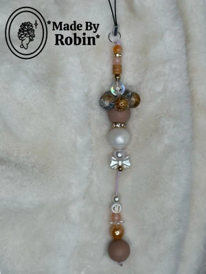 Charm ”Salted Caramel” 🤎🧡🤍 - Vår handgjorda charm ”Salted Caramel” med en karamell-liknande färg.🤎😇✨ Dekorerad med glittrande och matta pärlor och en söt liten rosett. Perfekt att hänga på väskan som en bag charm eller på mobilen 🥰✨