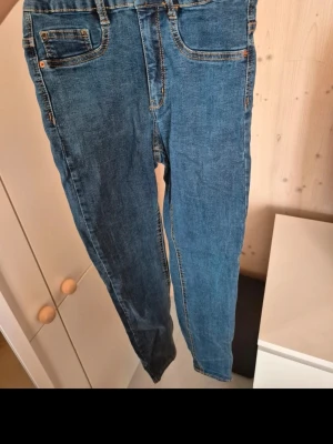 Blå Molly jeans - Säljer ett par klassiska blå Molly jeans från Gina Tricot. Modellen har smal passform, fem fickor och orangea sömmar. Jeansen är i stretchigt material för extra komfort och har normal midja.