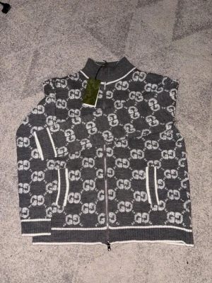 Gucci Cardigan Grå - Grå Gucci cardigan – helt ny & oanvänd Säljer en grå cardigan från Gucci i mycket fint skick. Tröjan är helt ny och oanvänd. Storleken är märkt XXL, men den sitter snarare som en L. Jag är storlek L och den passar mig perfekt.  Klassisk och stilren modell som passar både till vardags och mer uppklädda tillfällen.