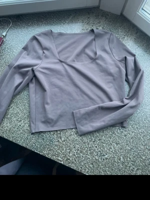 Tränings topp från ICANIWILL - Trendig brun/bege croppad topp från ICANIWILL med lång ärm och fyrkantig ringning. Tillverkad i mjukt och stretchigt material som sitter snyggt på kroppen. 