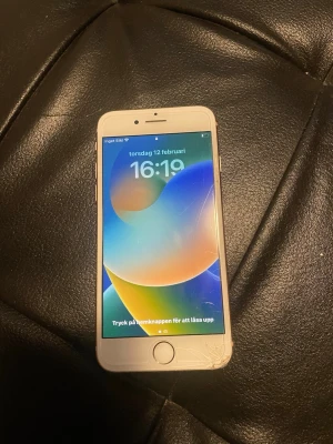 iPhone med vit ram och Touch ID - Säljer en iPhone med vit ram och rund hemknapp med Touch ID. Telefonen har en klassisk Apple-design med glasfront och aluminiumkanter. Skärmen är ljusstark och visar tydliga färger. Perfekt för dig som gillar iOS och smidig användning.