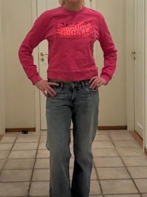 Rosa sweatshirt från Mads nordgaard  - Cool rosa sweatshirt från Mads nordgaard med glansigt tryck framtill. Tröjan har rund halsringning, långa ärmar och ribbade muddar vid ärmslut och nederkant. Perfekt för en avslappnad och trendig look.