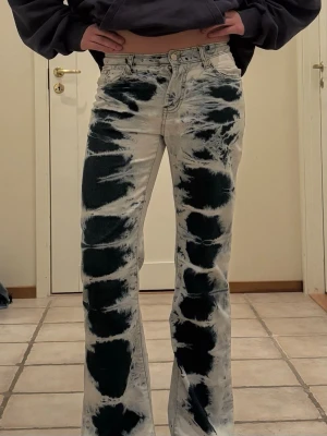 Svarta och vita tie-dye jeans - Unika svarta och vita tie-dye jeans med raka ben och hög midja. Snyggt mönster som sticker ut och ger en cool vibe. Perfekta för dig som vill ha något annorlunda i garderoben. Klassisk femficksmodell och knappgylf. Säljer för att de tyvärr blivit för små