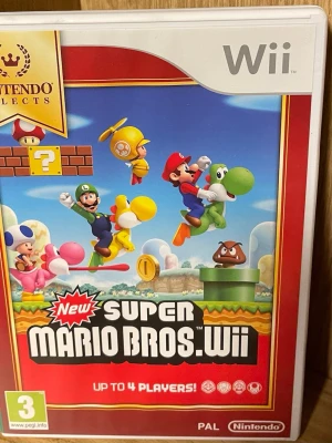 New Super Mario Bros. Wii spel - Roligt plattformsspel till Nintendo Wii där du kan spela som Mario, Luigi, Toad eller Yoshi. Omslaget är färgglatt med karaktärer i rött, grönt, blått och gult. Spelet är gjort av plast och papper och stödjer upp till fyra spelare. Nyskick