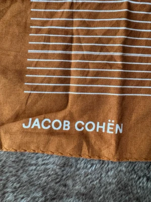 Jacob Cohën Scarf Limited Edition - Jacob Cohën scarf i färgen ”Burnt Orange” och är limited edition. Köpt på NK man och är aldrig använd. Passar perfekt på dig nu till sommaren ☀️Scarfen är 100% bommul. Orginalpris ligger på över 700kr! Mitt pris är inte hugget i sten så det är bara att höra av sig vid frågor eller funderingar 🙌🏼