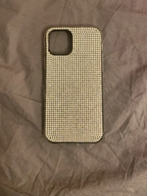 Glittrigt mobilskal med rhinestones  - Snyggt mobilskal täckt med små, glittrande strasstenar som ger en riktigt lyxig känsla. Skalets färg är silver och det har en rektangulär form med öppning för kameran. Perfekt för dig som vill ha ett skal som sticker ut och glänser. För iphone 12/12 pro❤️ skriv innan köp!!❤️