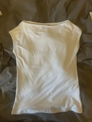 Vit ärmlös topp i bomull - En enkel och stilren vit topp i mjuk bomull. Modellen är ärmlös med rund halsringning och har en clean, minimalistisk look som passar till det mesta. Perfekt att matcha med jeans eller kjol för en fräsch outfit.