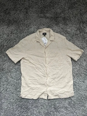 Beige linneskjorta från H&M - Säljer en stilren beige skjorta från H&M för 150kr! Skjortan är i storlek S.