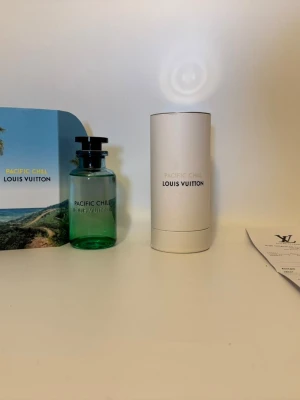 Louis Vuitton Pacific Chill parfym - Exklusiv parfym från Louis Vuitton, Pacific Chill. Flaskan är grön med svart lock och har en stilren, rund form. Kommer i elegant vit cylinderförpackning och ytterkartong med palmmotiv. Perfekt för dig som gillar lyxiga dofter och snygg design.