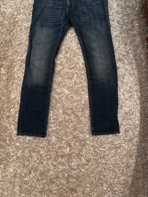 Dsquared 2 jeans  - Säljer ett par mörkblå jeans med raka ben och klassisk femficksdesign. Jeansen har snygga slitningar och en något tvättad look. Passformen är normal och materialet är robust denim som sitter skönt hela dagen. Storleken: W31 L32 nypris 1400kr