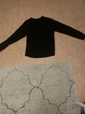 Svart sweatshirt med tryck - Svart sweatshirt med rund hals och trycket 'BLACK CAT 23' på bröstet. Tröjan har långa ärmar och ribbade muddar vid ärmslut och nederkant. Perfekt för en avslappnad och stilren look.