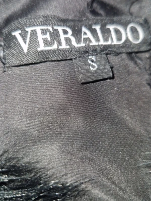 Svart pälsjacka från Veraldo - Snygg svart pälsjacka från Veraldo i storlek S. Jackan har en fluffig och lyxig look med horisontella paneler och rundad krage. Perfekt för att hålla värmen under kalla dagar. Tillverkad i mjukt fuskpälsmaterial som känns riktigt skönt.