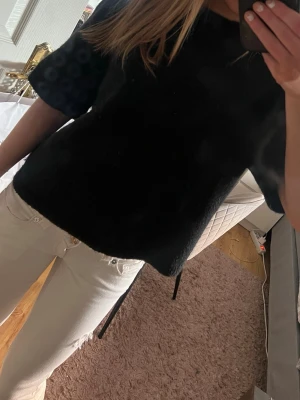 Svart kortärmad topp i mjukt material - En enkel och stilren svart topp med korta ärmar. Toppen har en rak passform och är gjord i ett mjukt, lite luddigt material som ger en mysig känsla. Perfekt att matcha med jeans eller kjol för en clean look.