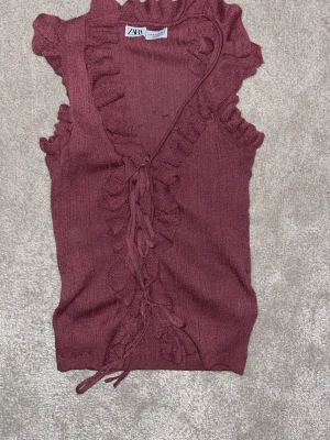 Vinröd volangtop från Zara - Supersöt vinröd topp från Zara med volangdetaljer längs kanterna och snörning framtill. Storlek S