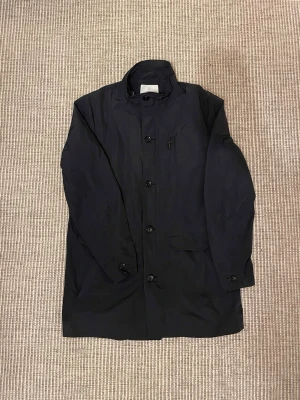 Bläck Vår Jacka  - En riktigt stilren vårjacka från märket Bläck. Lite längre passform som passar perfekt på våren men även hösten med en lite tjockare tröja under. Jackan är i storlek 54 och passar dig som brukar ha M/L. Jag är 193cm lång och jackan är lite för liten för mig. 