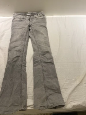Grå bootcut jeans från Perfect Jeans - Snygga grå bootcut jeans från Perfect Jeans med klassisk femficksdesign och dragkedjegylf. Jeansen har utsvängda ben och bälteshällor, perfekta för en trendig och avslappnad look. Tillverkade i mjukt denimtyg.