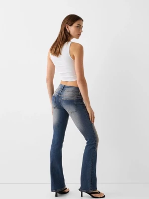 Blå bootcut jeans med slitningar - Bootcut jeans i blå denim med snygga slitningar och tvättade detaljer på framsidan och baksidan. Jeansen har klassisk femficksdesign, dubbla knappar och dragkedja. Perfekt för dig som gillar en cool och avslappnad stil.