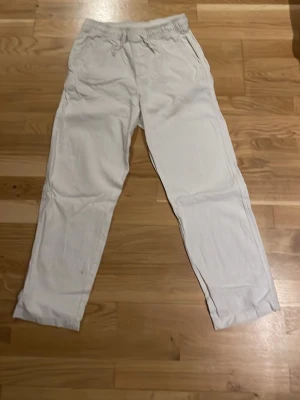 Vita linnebyxor från H&M - Säljer ett par vita linnebyxor från H&M med avslappnad passform och resår i midjan. Byxorna har raka ben och är tillverkade i ett lätt och luftigt linnematerial, perfekta för varma dagar. Klassisk och enkel design som passar till det mesta.