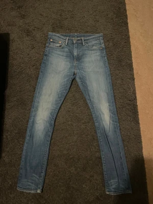 Ljusblå Levi's jeans med raka ben - Säljer ett par ljusblå jeans från Levi's med klassisk femficksdesign och raka ben. Jeansen har snygga slitningar framtill och bakfickor med den ikoniska Levi's-lappen. Perfekta för en avslappnad stil.