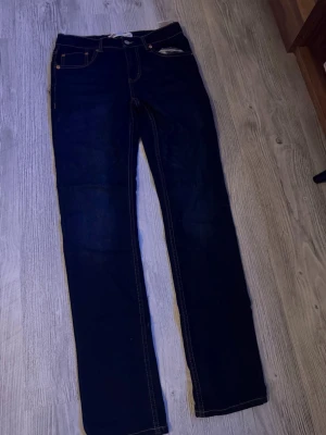 Mörkblå raka jeans från Levi's - Säljer ett par klassiska mörkblå jeans från Levi's med raka ben och kontrastsömmar. Jeansen har fem fickor och en patch med Levi's-logga bak i midjan. Perfekta för dig som gillar tidlös denimstil.