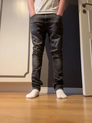 Nudie jeans  - Grå jeans ifrån Nudie. Storlek W29 L30. Jeansen är i bra skick förutom en skada precis under gylfen men som inte syns vid användning eller påverkar på annat sätt. Jeansen har en slim/straight passform. Hör av er vid minsta fundering 🤔 🎉