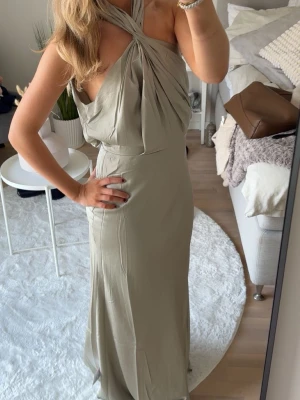 Ljusgrön satinklänning  - Elegant ljusgrön långklänning med omlottdetalj och draperad halterneck. Aldrig använd, men perfekt till balen💃🏼