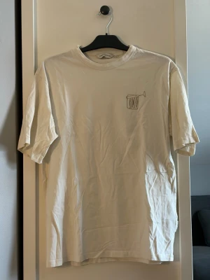 Beige t shirt med silltryck - Vit t-shirt från Casual friday med silmotiv tryckt på bröstet och text på ryggen. Klassisk passform med rund hals och korta ärmar. Tillverkad i mjuk bomull som känns skön mot huden. Perfekt för en avslappnad och stilren look.