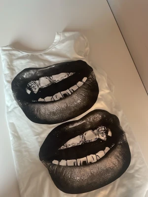 Super snygg t-shirt - en jättefin vit T-shirt med ett tryck av 2 läppar. väldigt fint till en kjol. Endast använd 2 gånger❤️
