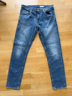 Blå jeans från Tiger of Sweden modell Pistolero - Säljer ett par klassiska blå jeans från Tiger of Sweden i modell Pistolero. Jeansen har en snygg tvättad look med ljusare partier och detaljer i metall. 
