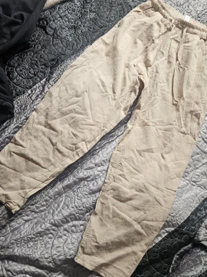 Beiga linnebyxor med resårmidja - Snygga och avslappnade beiga linnebyxor med resår i midjan. Perfekta för varma dagar och har en loose passform som ger en chill vibe. Byxorna är enkla att matcha med olika toppar och passar till många tillfällen.