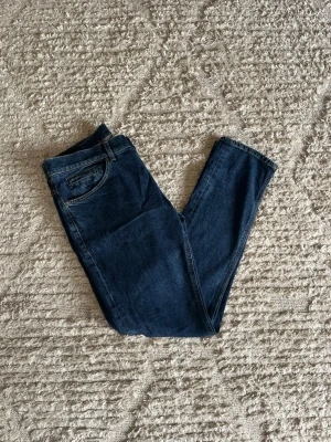 Dondup George jeans  - Säljer nu dessa fina marinblåa Dondup George jeans i nyaste årsmodell, nypris 4000kr. Inga defekter eller skador 9/10. Midja: 43cm. Lår: 27cm. Ytterlängd: 104cm. Innerlängd: 80cm. 