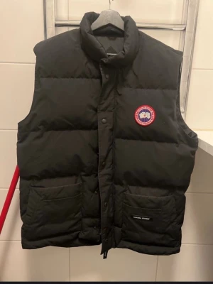Svart dunväst från Canada Goose, herr  - Dun väst. Fint skick förutom lite blekt vid fickor samt liten fläck på insidan. Inget märkvärdigt. Storlek XL herr modell. 
