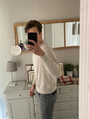 Beige tröja från Gant - Snygg beige tröja från Gant med rund halsringning och diskret logga på bröstet. Tröjan har en klassisk passform, långa ärmar och ribbade muddar vid ärmslut och nederkant. Perfekt för en stilren och enkel look. A41, B 49 C 63 D 58