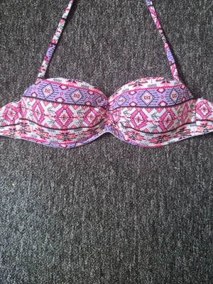 bikini i rosa och lila - Snygg bikini med mönster i rosa, lila och vitt. Klassisk trekantsmodell med smala axelband som knyts i nacken och ryggen. Perfekt för sommardagar på stranden eller vid poolen.