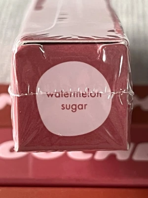 Smooche Stick & Stain Watermelon Sugar - Snyggt läppstift från Smooche i nyansen Watermelon Sugar. Förpackningen är rosa med vit text och läppstiftet är i stickform. Perfekt för dig som vill ha en fräsch och somrig färg på läpparna. Materialet är klassisk plastförpackning.