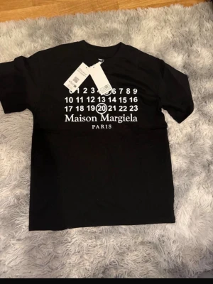 Maison Margiela t-shirt - Svart t-shirt från Maison Margiela riktigt snygg go logga, skönt bomulls material, perfekt för sommarn storlek 44 samma som S pris ej fast mvh!