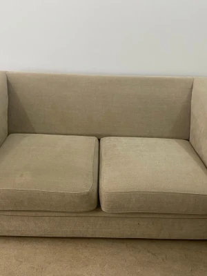 Beige 2-sits designsoffa - Säljer en beige 2-sits soffa med unik modern design och mjukt tyg. Väldigt bekväm och passar perfekt i vardagsrum eller lägenhet. Använd i cirka 3 år. Finns mindre fläckar/slitage från användning men överlag i fint skick. Syns inte mycket enligt mig. (📍 Endast upphämtning i Göteborg)