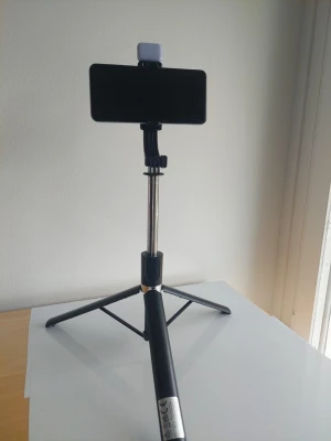 1.7m Selfiestick med stativ och LED-belysning - Praktisk selfiestick med inbyggt stativ och justerbar hållare för mobil. Utrustad med två små LED-lampor för bättre belysning vid foto eller video. Svart och silverfärgad med teleskopfunktion. Perfekt för selfies, videoinspelning eller streaming.