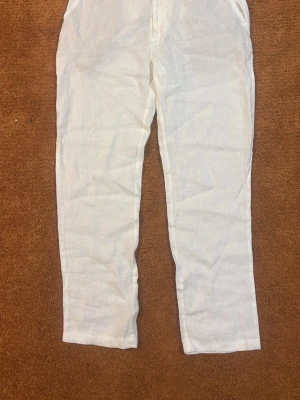 Vita linnebyxor från Dressmann - Snygga vita linnebyxor från Dressmann i 100% linne. Byxorna har rak passform och klassisk design med fickor i sidorna. Perfekta för en avslappnad och stilren look under varma dagar.
