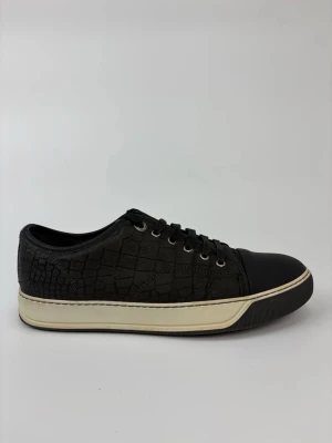 Svarta Lanvin sneakers med crocomönster - Stilrena svarta sneakers med crocomönstrad ovandel och svarta tåpartier. Skorna har vita sulor med svarta detaljer och metallfärgade öljetter. Perfekta för dig som gillar en clean look med lite edge.