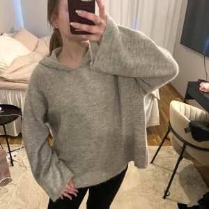 Grå stickad hoodie med vida ärmar - Mysig grå stickad hoodie med avslappnad passform och vida ärmar. 