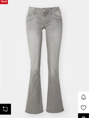 Grå bootcut jeans med utsvängda ben - Snygga grå bootcut jeans med utsvängda ben och klassisk femficksdesign. Jeansen har låg midja och stängs med knapp och dragkedja. Perfekta för en trendig och avslappnad look.