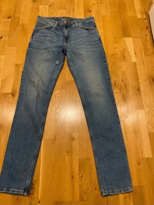 Collins Blå raka jeans med slitning W34 L34 - Klassiska blå jeans med rak passform och lätt slitning på vänster lår. Jeansen har fem fickor och normal midja. Perfekta för en avslappnad och tidlös look. Materialet är denim i bomull.obs litet hål eller slitning på insidan se bild