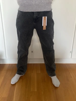 Svarta/mörkgrå jeans från grunt - Mörkgråa jeans från grunt i storlek W29. Personen på bilden är 180cm. Aldrig använda, prislapp kvar! Köpta för 599kr Pris kan diskuteras vid snabb affär!