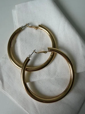guldiga hoops örhängen - Säljer ett par klassiska hoops i guldtonad metall. De har en rund, tjock form och enkel låsning 🤍