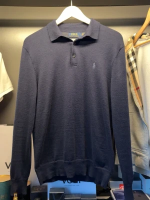 Marinblå merinoull långärmad piké från  Polo Ralph Lauren - Klassisk marinblå långärmad pike från Polo Ralph Lauren i mjuk och tvättbar merinoull. Tröjan har krage, knappslå med 3 knappar och diskret broderad logga på bröstet. Perfekt för en stilren och avslappnad look. Den är i bra skick säljer den endast pågrund av ingen användning. (Nypris 2700) bevis på att den är äkta finns också och priset är inte hugget i sten. Skulle kunna passa folk med S också 