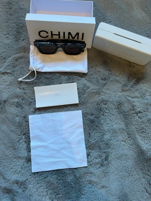 Chimi - Stilrena gråa solglasögon från CHIMI med fyrkantig form och mörka glas. Kommer med originalförpackning, fodral och putsduk. Perfekta för dig som vill ha en klassisk och trendig look. Pris kan diskuteras vid en snabb affär riktigt bra skick på dom med. Hör av er vid några frågor🍾