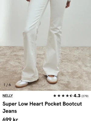 Vita bootcut jeans från Nelly - Säljer ett par vita bootcut jeans från Nelly med superlåg midja och hjärtformade bakfickor. Jeansen har en snygg utsvängd passform och är perfekta för dig som gillar trendiga detaljer och en clean look. Materialet är klassiskt denim.